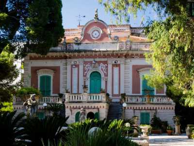 Ci appare con il suo delicato rosso pompeiano che si unisce al bianco degli ornamenti e al verde delle persiane